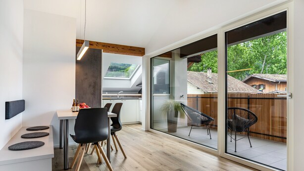 A modern kitchen with a dining area, large sliding glass doors, and a view of a wooden deck. - Apartment '1' with Mountain View, Wi-Fi and Air Conditioning (Auer)
