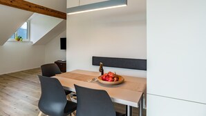 A modern dining area with a table, chairs, a bowl of fruit, and a pendant light. - Apartment '1' with Mountain View, Wi-Fi and Air Conditioning (Auer)