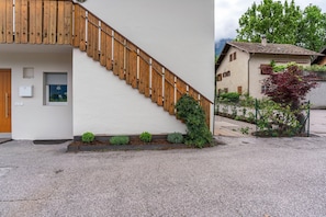 A building with a wooden staircase, a door, and a small garden area with various plants. - Apartment '2' with Mountain View, Wi-Fi and Air Conditioning (Auer)