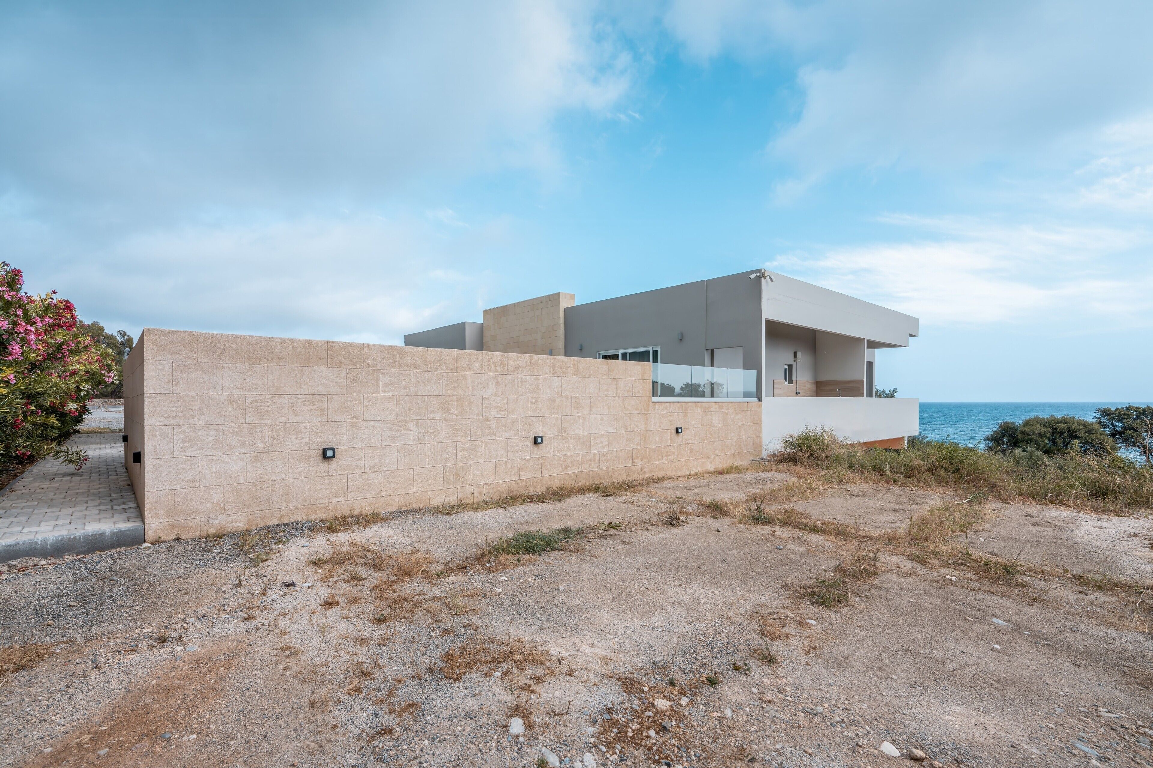 Ein modernes Haus mit flachem Dach, einem Balkon und Blick auf das Meer.