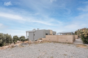 Een modern gebouw met een plat dak, een betonnen muur en een grindpad.