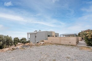 Um edifício moderno com telhado plano, parede de concreto e chão de cascalho.