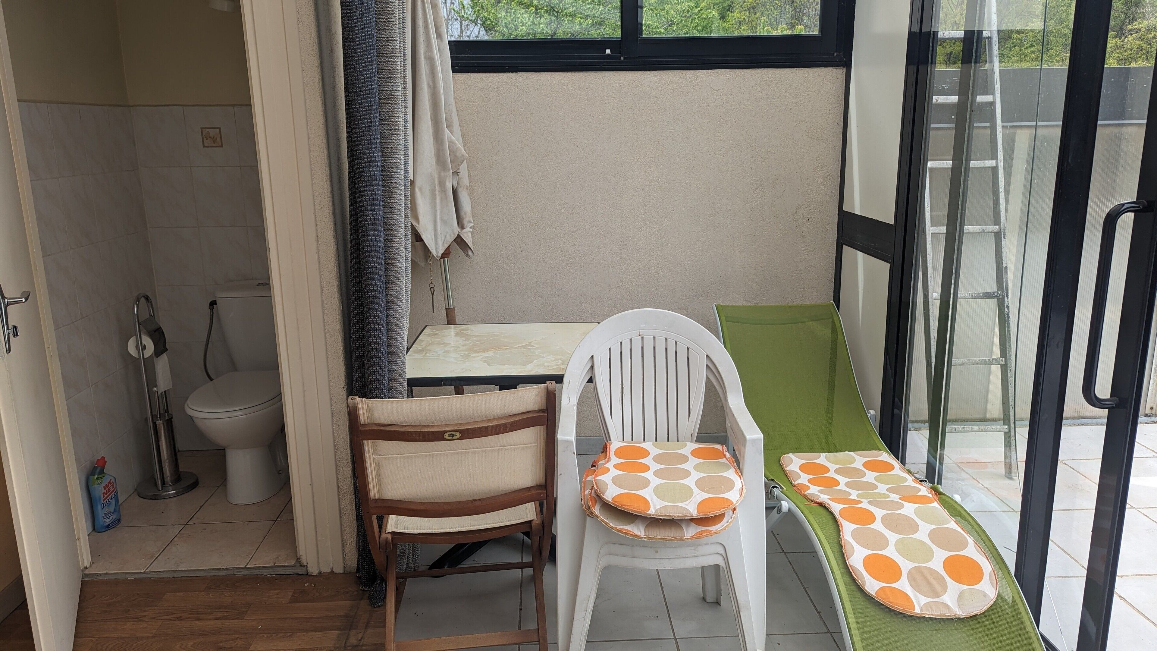 A small room with a toilet, a chair, a table, and a bench.