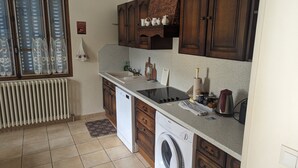 A kitchen with a washing machine, a stove, and wooden cabinets.