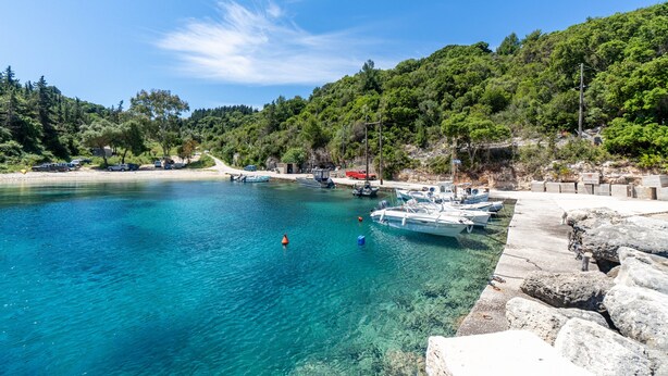 A coastal area with clear water, boats, and a rocky shoreline.