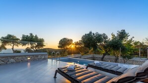 A rooftop pool area with lounge chairs and a stone wall.