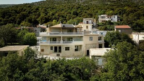 Un immeuble à plusieurs étages, doté de balcons, entouré d’arbres et ayant une chaîne de montagnes en toile de fond.