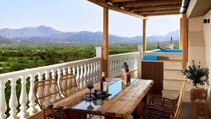 Un balcon avec une table en bois, des chaises en osier et une vue sur les montagnes.