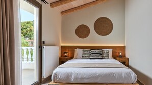 Une chambre avec un lit en bois, deux tables de chevet avec des lampes, une vue à travers une porte vitrée et deux éléments décoratifs en fibres tressées accrochés au mur.