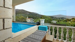 A balcony with a pool, a lounge chair, and a view of a mountainous landscape. - Apartment 'Villa 2' with Mountain View, Balcony and Wi-Fi (Plati/Lasithi)