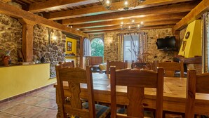 A rustic dining area with wooden beams, stone walls, and a chandelier.