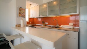 A modern kitchen with white cabinets, a stainless steel sink, and a white countertop. - Apartment 'Mirada I' with Open Views, Wi-Fi, and Air Conditioning (Es Pujols)