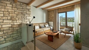 A modern living room with a stone wall, wooden beams, a sofa, a coffee table, a chair, a potted plant, and a balcony with a view.