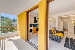En moderne lejlighed med balkon, køkken, sofa og spiseplads.
