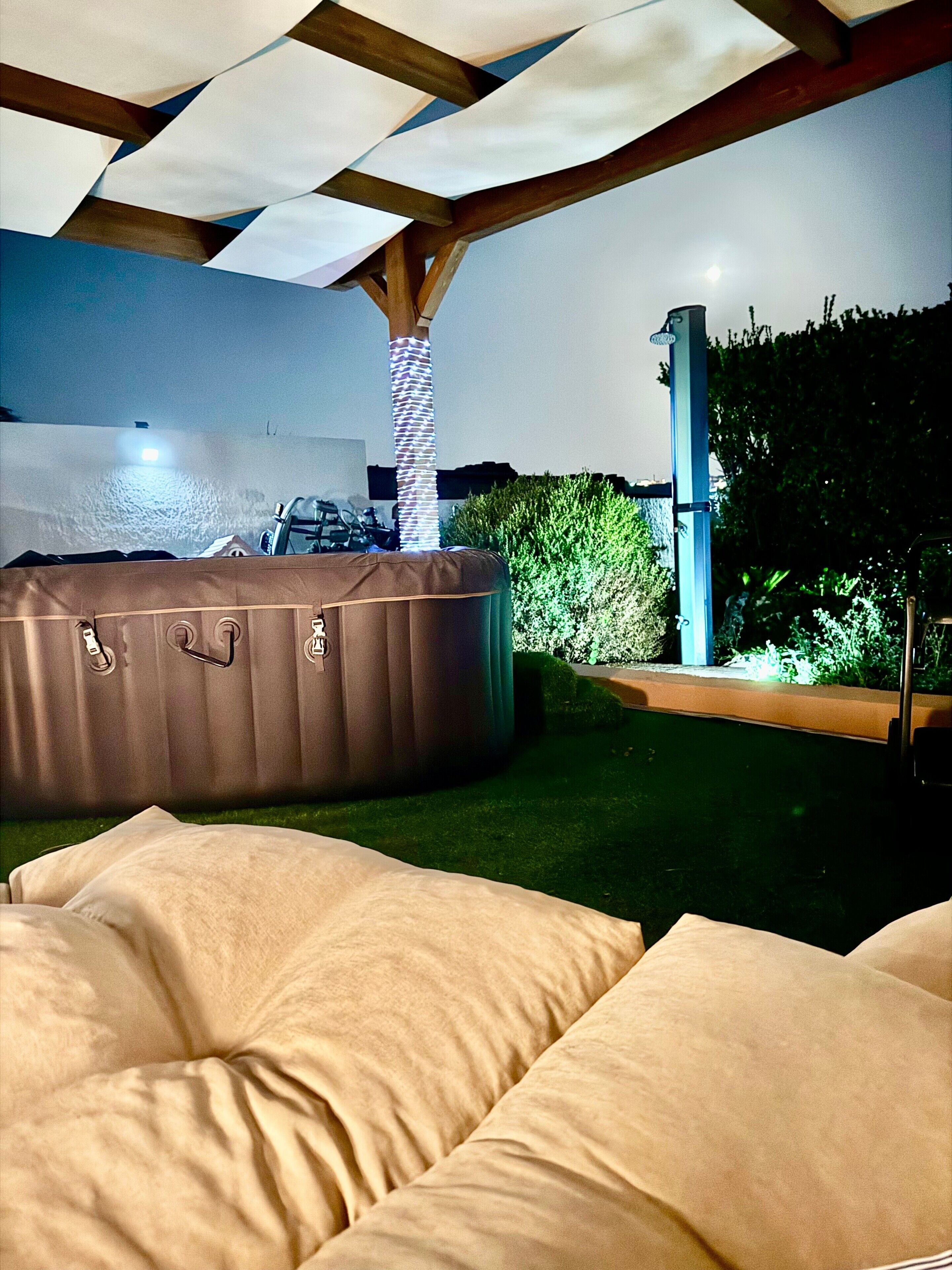 An outdoor seating area with a hot tub and a pergola structure.