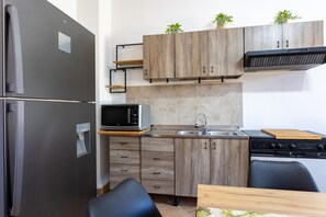 Une cuisine compacte équipée d’un réfrigérateur, d’un four à micro-ondes, d’un évier et d’une cuisinière.
