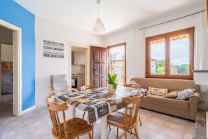Un espace repas comprenant une table, des chaises, un canapé et une vue par la fenêtre.
