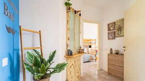 A hallway with a blue wall, a wooden bench, a potted plant, a mirror, and a wooden cabinet.