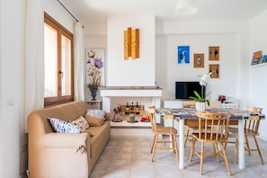 Un salon comprenant un canapé, une table à manger avec des chaises, une cheminée et des œuvres d’art murales.