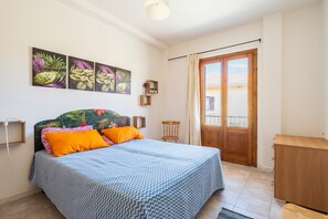 Une chambre à coucher avec un lit, une armoire en bois, une fenêtre avec des rideaux et des œuvres d’art murales.