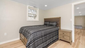 Un dormitorio con cama, mesita de noche y ventana.