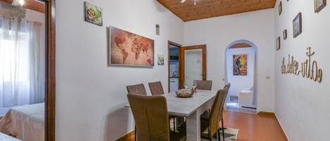 Zona de menjador amb sostre de fusta, un quadre gran i una paret amb imatges emmarcades.