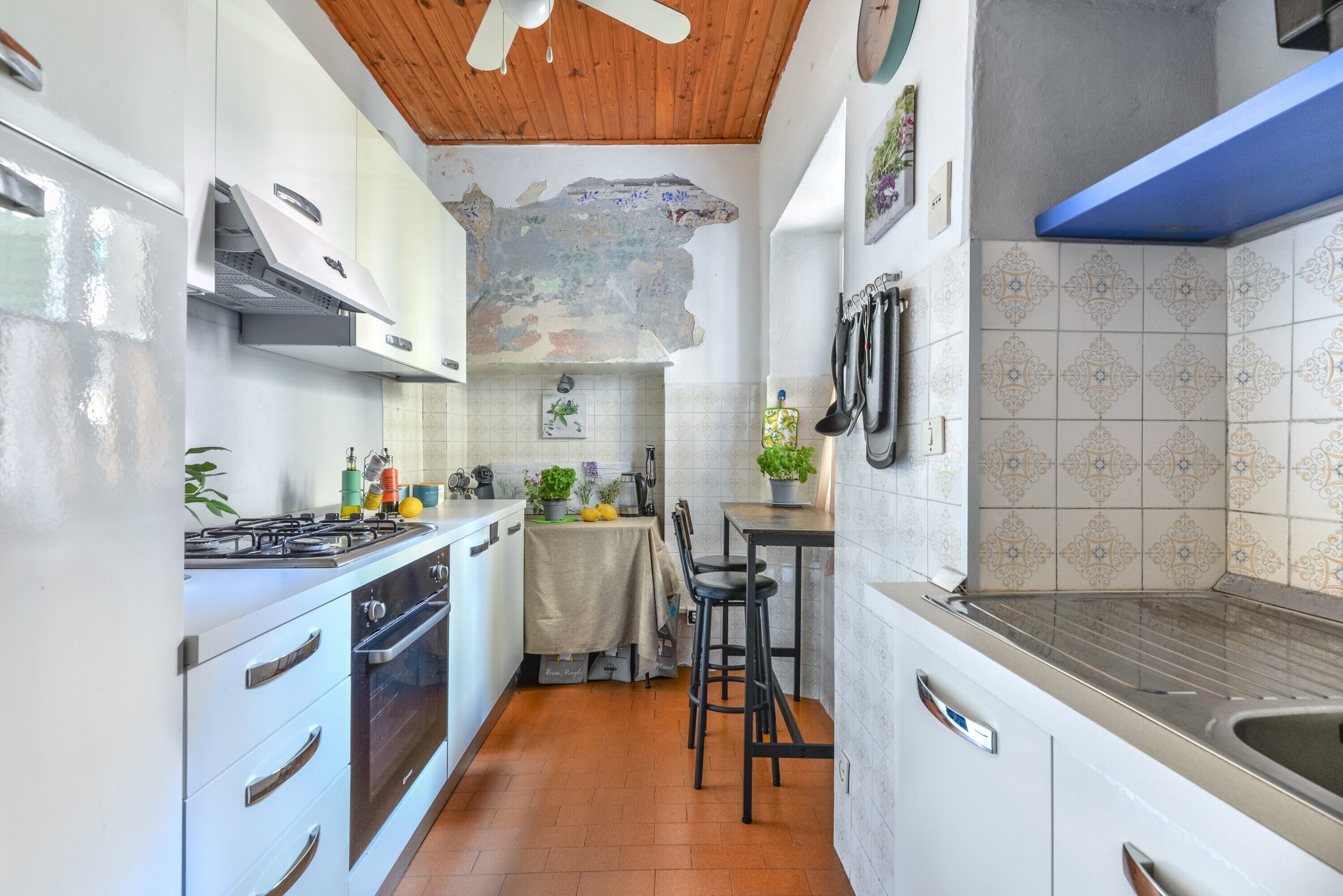 Una cocina con armarios blancos, una estufa y un comedor con mesa y sillas.