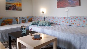 Quarto com uma cama, uma mesa, um mapa-múndi, uma pintura de pôr do sol e uma luminária de parede.