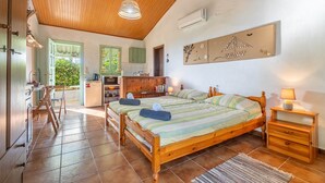Un dormitorio con una cama de madera, una mesita de noche, una silla, un escritorio y una zona de cocina con ventana.