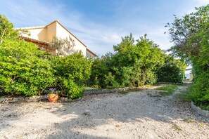 A house with a gravel driveway, surrounded by dense greenery and a clear sky. - Seafront Studio Stefan with Sea View, Private Terrace, and Air Conditioning (Corfu)
