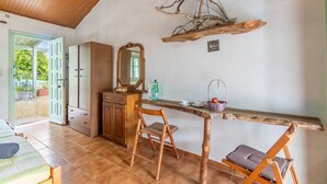 Una habitación con techo de madera, un escritorio de madera con una silla, un espejo y una lámpara rústica colgante.