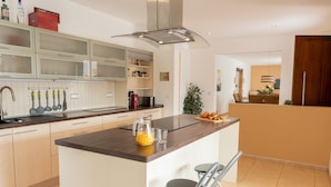 A modern kitchen with a central island, stainless steel appliances, and a dining area with a view. - Villa 'Paulina' with Mountain View, Wi-Fi and Air Conditioning (Xàbia)