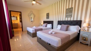 A hotel room with two beds, a ceiling fan, a mirror, a striped wall, and a bedside table with a lamp. - Villa 'Paulina' with Mountain View, Wi-Fi and Air Conditioning (Xàbia)