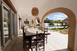 An outdoor dining area with a table and chairs, a pool, and a view of the surrounding landscape. - Villa 'Paulina' with Mountain View, Wi-Fi and Air Conditioning (Xàbia)