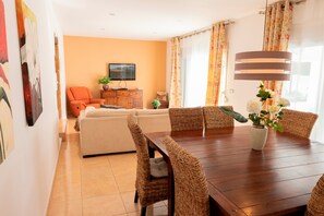 A dining area with a wooden table and wicker chairs, a sofa, and a television in the background. - Villa 'Paulina' with Mountain View, Wi-Fi and Air Conditioning (Xàbia)
