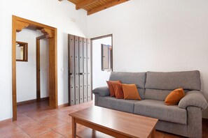 A living room with a grey sofa, wooden table, and a door with a mirror.