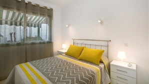 Une chambre à coucher avec un lit, deux tables de chevet avec des lampes, une fenêtre avec des rideaux et une vue sur les bâtiments à l’extérieur.
