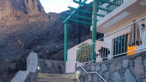 Un escalier menant à un bâtiment aux murs de pierre et dont la rampe est en métal.