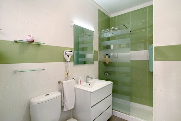 Une salle de bain équipée de toilettes, d’un lavabo et d’une douche à parois en verre.