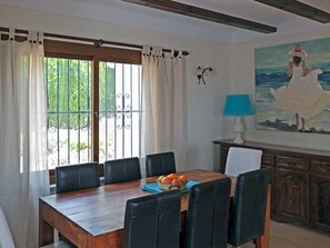 Ein Esszimmer mit einem Holztisch, schwarzen Stühlen, einer Obstschale und einem Gemälde einer Frau an der Wand.