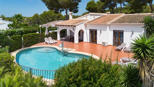 Un espace aménagé au bord de la piscine, comprenant une piscine, des chaises longues et un bâtiment blanc doté d’un toit en tuiles.