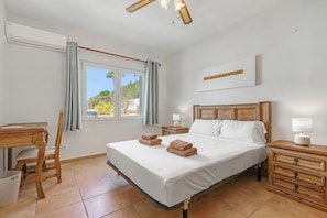 Ein Schlafzimmer mit Bett, Schreibtisch, Stuhl, Nachttisch und einem Fenster mit Vorhängen.