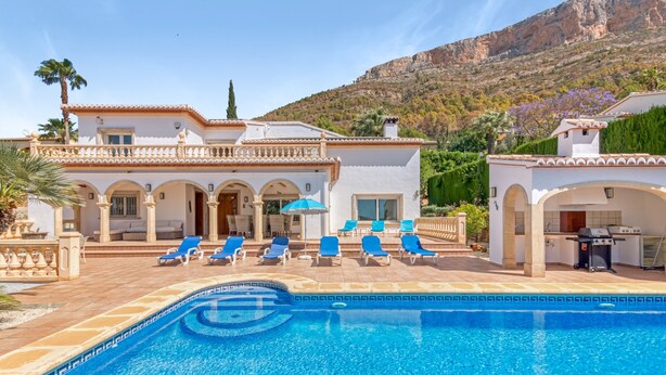 A pool with blue water, a white building with arches, and a mountain in the background. - Villa 'Cristina' with Mountain View, Wi-Fi and Air Conditioning (Xàbia)