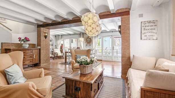 A spacious living room with a high ceiling, exposed brick walls, and a large window. - Villa 'La Siesta' with Mountain View, Private Pool and Wi-Fi (Xàbia)