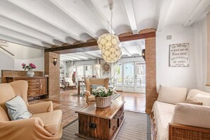 A spacious living room with a high ceiling, exposed brick walls, and a large window. - Villa 'La Siesta' with Mountain View, Private Pool and Wi-Fi (Xàbia)