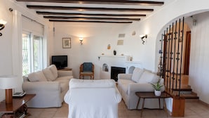 A living room with two sofas, a television, a fireplace, and a staircase with a railing. - Villa 'La Paz' with Private Pool, Shared Terrace and Wi-Fi (El Tosalet)