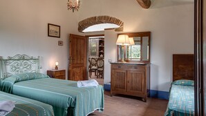 Een slaapkamer met twee bedden, een houten dressoir, een spiegel en een kroonluchter.