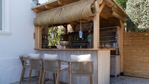 Un'area con un bancone bar in legno, due sedie in vimini e diverse bottiglie.