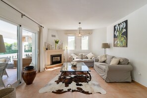 A living room with a glass coffee table, a sofa, a fireplace, and a large window. - Villa 'Bonita' with Private Pool, Wi-Fi and Air Conditioning (Capsades)