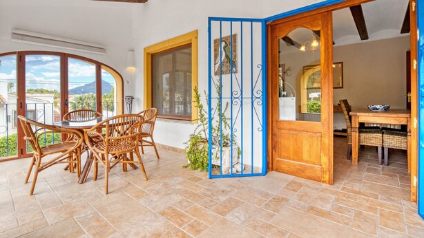 A dining area with a round table and chairs, a blue gate, and a view of the outdoors. - Villa 'Nichola' with Private Pool, Wi-Fi and Air Conditioning (Xàbia)